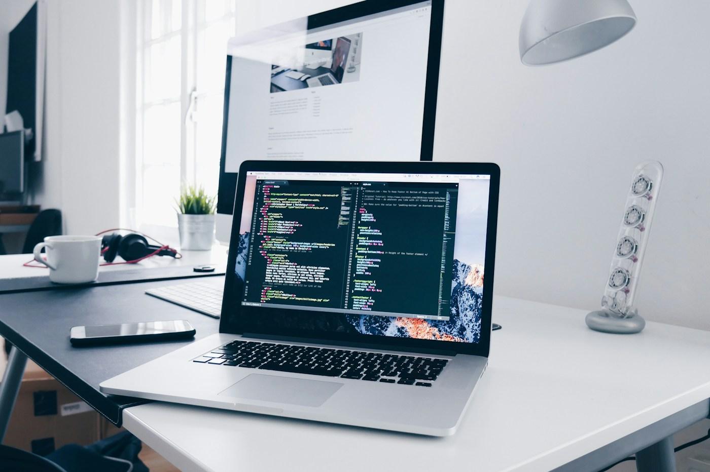 Laptop displaying software code at a working desk